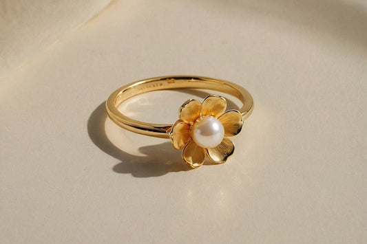 Gold flower ring with a pearl center, delicate and elegant design.