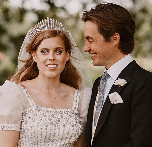 Princess Beatrice in her wedding dress with a sparkling tiara, standing beside her husband Edoardo Mapelli Mozzi on their wedding day, sharing a joyful moment with smiles.