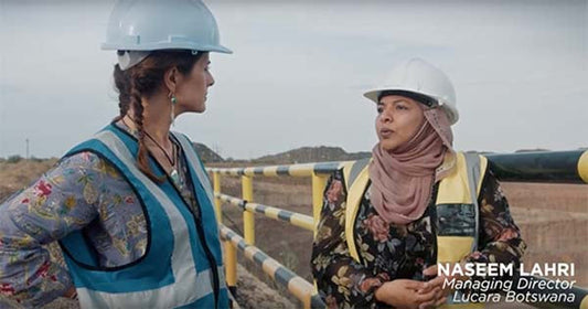 Two women in construction gear discussing at a mining site, one wearing a hard hat and vest, with Naseem Lahri, Managing Director of Lucara Botswana, introduced in the caption.