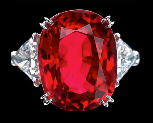 Close-up of a luxurious red ruby ring with a large oval-cut ruby surrounded by two triangular diamonds on each side, set in white gold or platinum, showcasing its stunning color and brilliance.