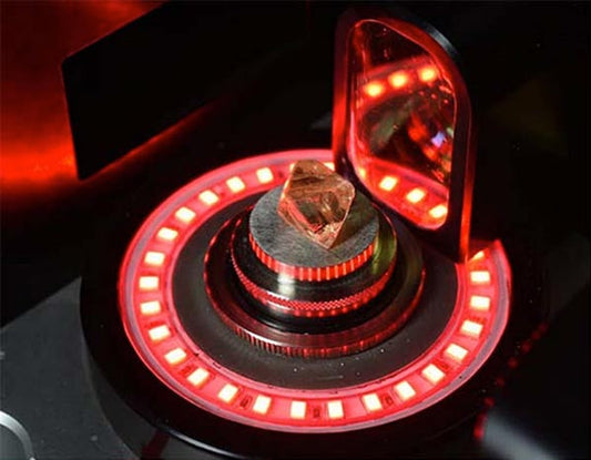 Close-up of a diamond being analyzed in a high-tech scanner with red LED lighting, showcasing its intricate facets and precision measurement.