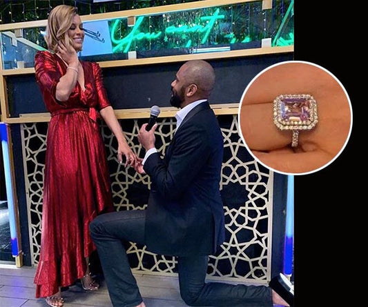 Man proposing to a woman in a red dress with a diamond engagement ring, in front of a decorated background with neon lights.