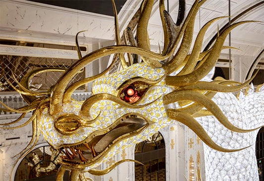 Intricate gold and diamond dragon sculpture with glowing red eyes, displayed in a luxurious setting.