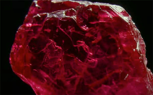 Close-up view of a deep red ruby gemstone, showcasing its intricate natural inclusions and vivid color, captured with high detail.