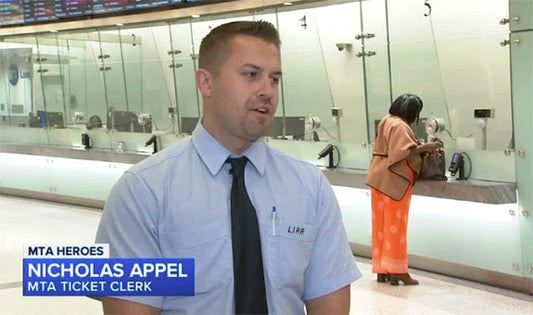 MTA ticket clerk Nicholas Appel being interviewed in front of ticket windows at a train station, with a customer in the background.
