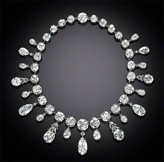 Elegant diamond necklace featuring a series of sparkling pear-shaped and round diamonds, arranged in a sophisticated design, against a dark background.