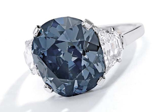 Elegant white gold ring featuring a large blue sapphire center stone with two clear diamonds on the sides.