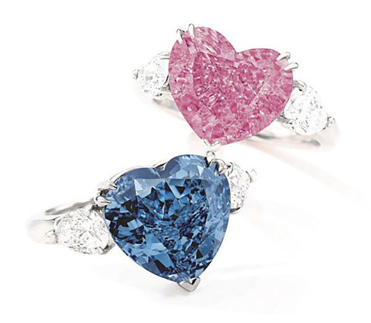 Two elegant heart-shaped diamond rings featuring a pink diamond and a blue diamond, each complemented by side diamonds, showcasing luxury and beauty in fine jewelry.