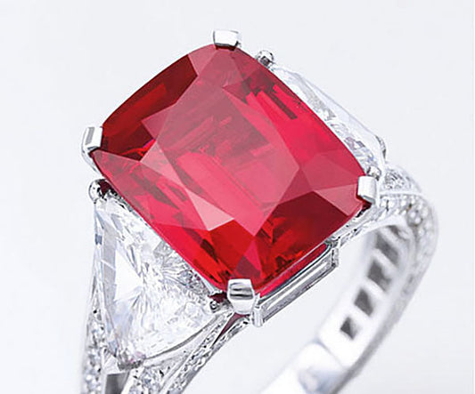Close-up of a luxurious ruby engagement ring with a large red rectangular ruby gemstone and two diamond side stones, set in a white gold band, showcasing its intricate design and elegance.