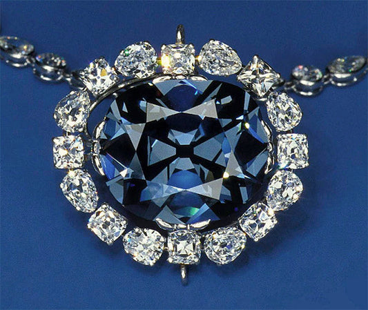 The Hope Diamond, a large blue diamond surrounded by smaller white diamonds on a necklace, displayed against a blue background.