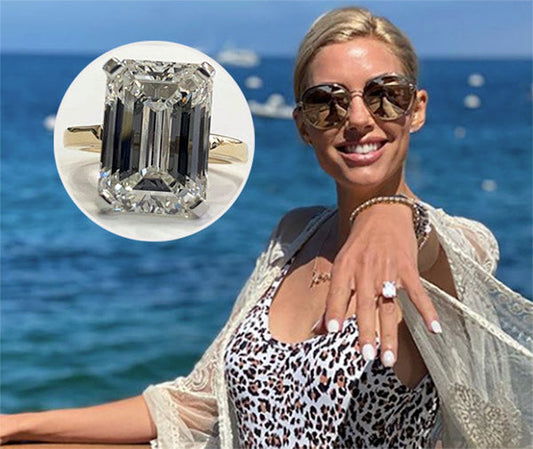 Engagement ring with a large emerald-cut diamond showcased on a woman's hand with a stunning beach backdrop. The image highlights the elegant, intricate design of the diamond ring with alternating baguette diamonds.
