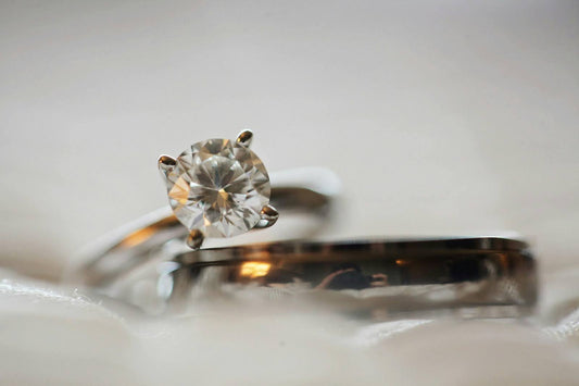 Close-up of a diamond engagement ring with a round cut diamond set in a white gold band, with a matching wedding band.