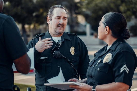 Los Angeles police officers discussing a report in uniform, one officer speaking while the other listens.