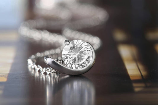 Close-up of a sparkling diamond pendant with a modern swirl design, set on a silver chain.