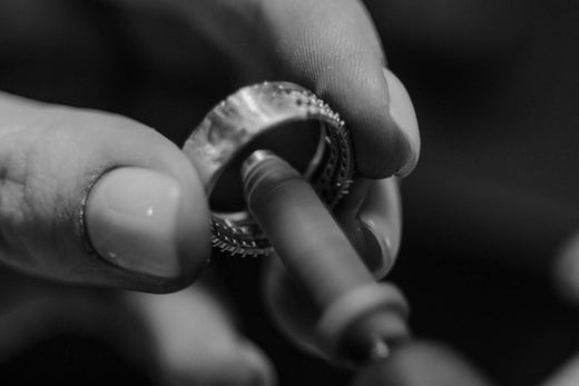Jeweler polishing a silver ring with a tool, showcasing fine craftsmanship.