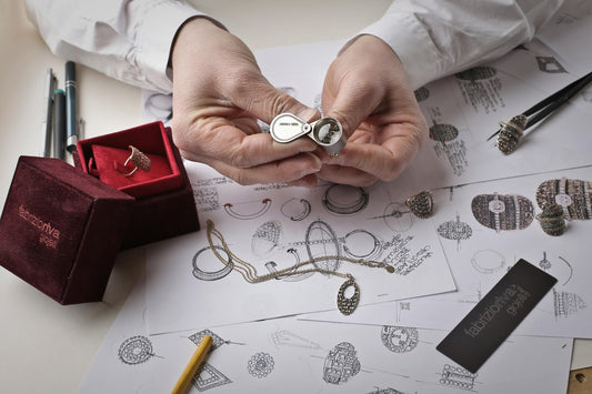 Jewelry designer examining a detailed ring design, surrounded by sketches, jewelry pieces, and tools.