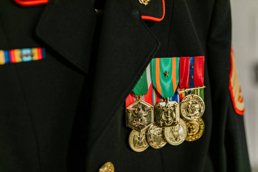 Close-up of military uniform displaying multiple medals and ribbons on a black jacket.