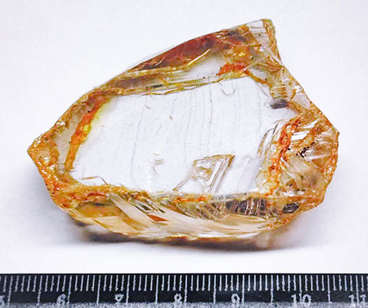 Large rough diamond crystal with visible natural imperfections, measured with a ruler for scale.