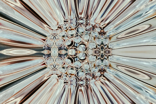 Abstract close-up of a diamond jewelry piece with a reflective surface and intricate design, featuring circular diamond patterns and sharp angular reflections.