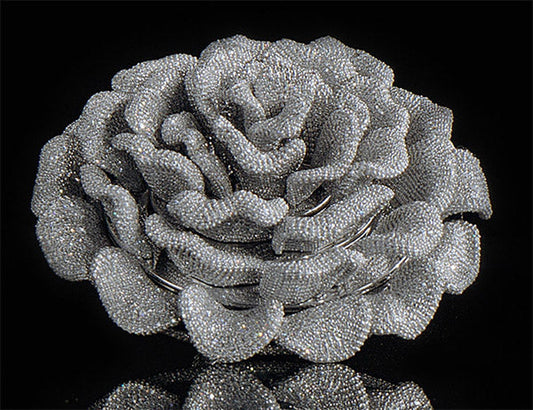 A sparkling diamond-encrusted brooch shaped like a rose, displayed against a black background.