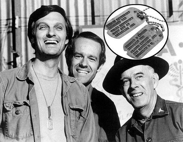 Black and white photo from the TV show MAS*H featuring Alan Alda, Mike Farrell, and Harry Morgan smiling together, with a close-up of their dog tags in the inset.
