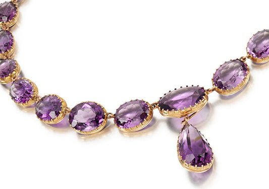 Elegant amethyst necklace featuring a series of oval and pear-shaped purple gemstones set in gold, designed for luxury and sophistication.