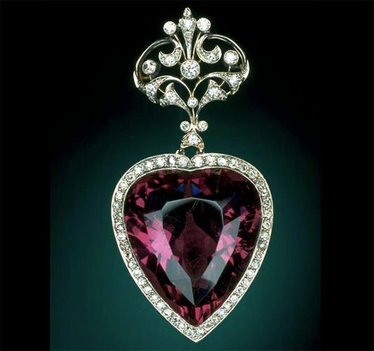 Heart-shaped purple gemstone pendant surrounded by diamonds, with an ornate diamond-studded top design.