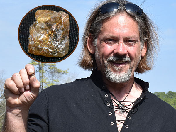 A man holding a gemstone in his hand, with a close-up view of the gemstone in an inset image, while smiling outdoors.