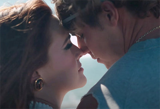 Close-up of a couple gazing at each other with their faces inches apart, sharing a romantic moment outdoors with soft sunlight and blurred background, capturing the essence of love and intimacy.