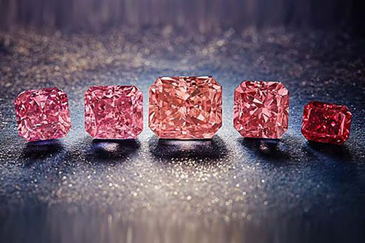 Five sparkling pink diamonds arranged in a row, showcasing various sizes and cuts, set against a shimmering dark background.