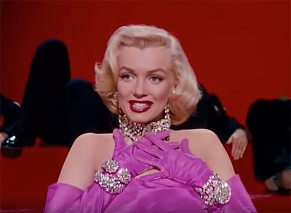 Marilyn Monroe wearing glamorous pink gloves and sparkling jewelry, performing on stage with a striking red background, iconic look from 'Gentlemen Prefer Blondes.