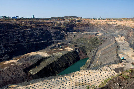Large open-pit mining site with visible machinery, dirt, and a body of water in the center.