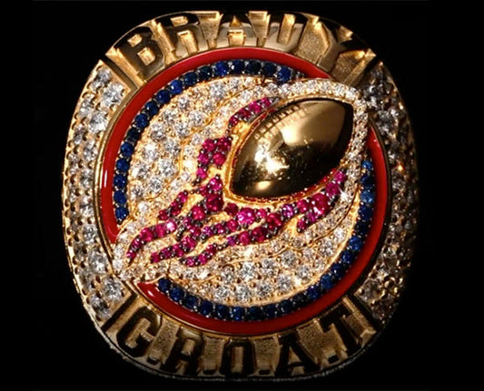 Super Bowl championship ring featuring the name 'Brady' with a football design, surrounded by diamonds and rubies.
