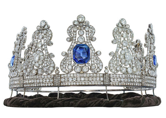 Luxurious diamond and sapphire tiara featuring intricate designs with large blue sapphires and multiple sparkling diamonds, set on a velvet base.