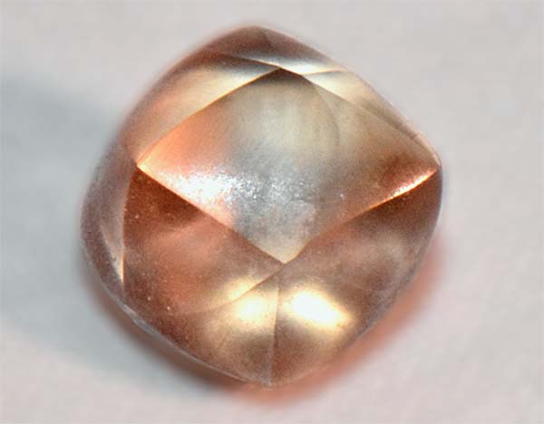 Close-up of a light-colored, faceted gemstone with a smooth, polished surface.