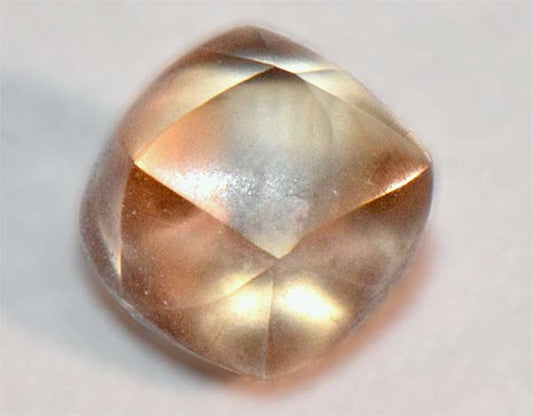 Close-up of a light-colored, faceted gemstone with a smooth, polished surface.