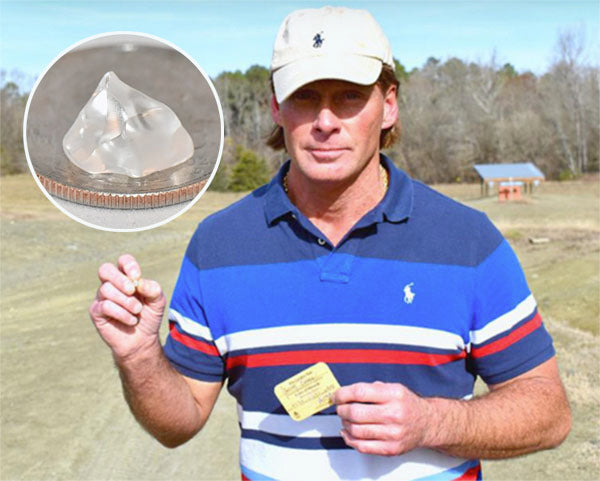 Man holding a clear diamond-like crystal he discovered, with an inset showing the crystal next to a coin for size comparison.