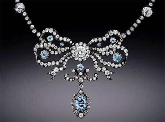 Elegant vintage necklace featuring a diamond-studded bow design with blue and white gemstones, showcasing intricate craftsmanship and a luxurious aesthetic.