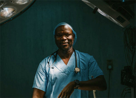 Smiling African-American surgeon wearing scrubs and stethoscope in operating room, ready for surgery.