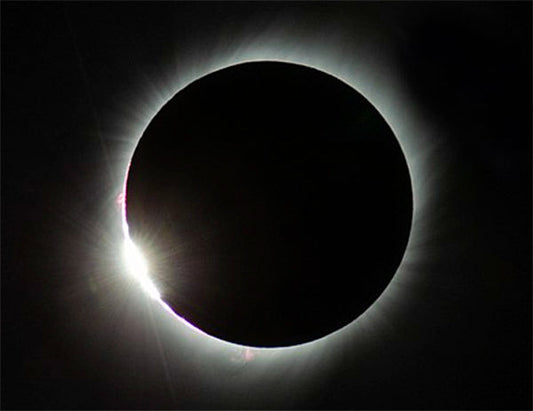 Total solar eclipse showing the darkened moon with the sun's corona visible around its edges, captured during the celestial event.