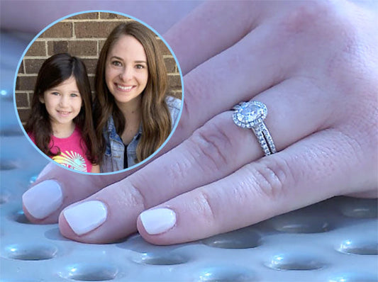 Close-up of a hand with an engagement ring, featuring a diamond band and oval-cut center stone. An inset shows a woman with her young daughter, smiling together outdoors.