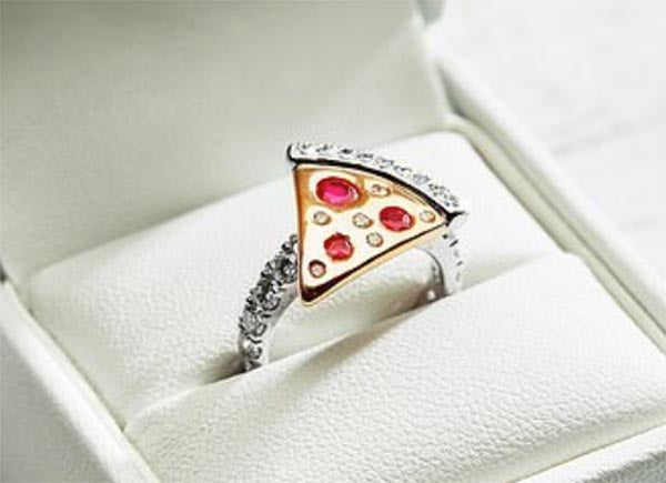 Unique pizza slice ring with ruby-like gemstones as toppings and sparkling diamonds on the band, set in a luxurious white ring box.