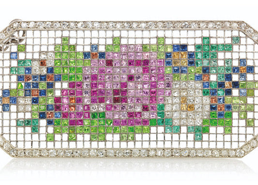 Close-up of a colorful floral clutch purse embellished with multicolored gemstones, including pink, green, blue, and yellow, set in a diamond-like grid design.