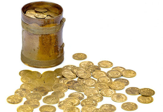 A canister filled with ancient gold coins, with several coins scattered around the base, showcasing a collection of historical currency.