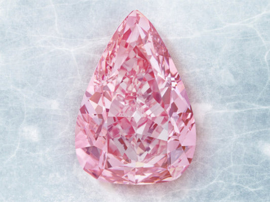 A large, teardrop-shaped pink diamond with sparkling facets on a light blue background.
