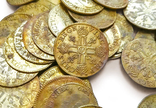 A close-up view of old vintage coins with intricate designs, featuring crowns and crosses, symbolizing historical currency.