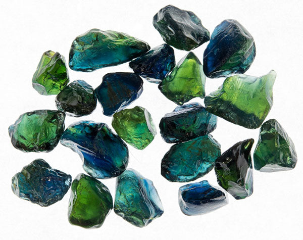 Collection of raw blue and green sapphires scattered on a white background, showcasing the natural beauty and vibrant colors of the gemstones.
