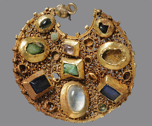 Ancient gold pendant with various gemstones, including emeralds, sapphires, and quartz, set in an intricate design.