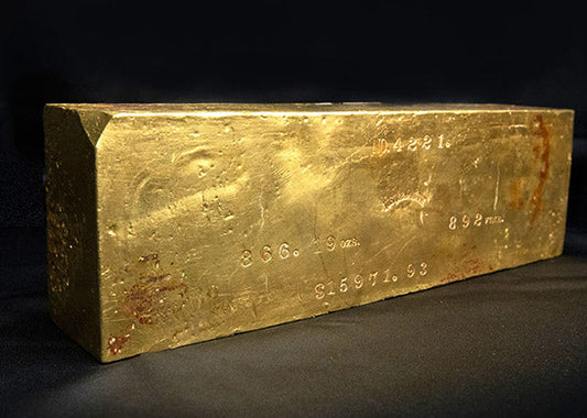Gold bullion bar with engraved markings and serial number on a black background.