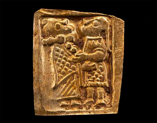 Ancient carved stone depicting two human figures holding hands, with stylized details of their clothing and faces, symbolizing an historical scene or story.